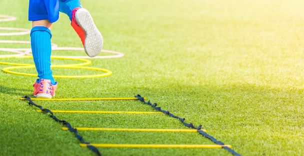 Kindervoeten met voetbalschoenen training op Agility Speed ladder in - Foto, afbeelding
