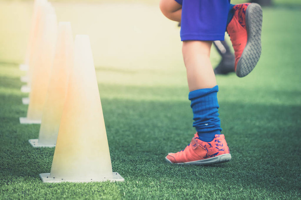 サッカーブーツで子供の足は、ソック上のトレーニングコーンで訓練 - 写真・画像