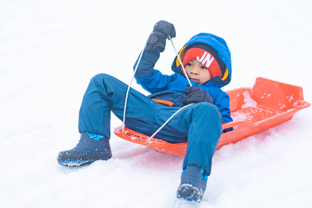 日本の少年が雪のそりを滑り降りています｜Yuzawa - 写真・画像