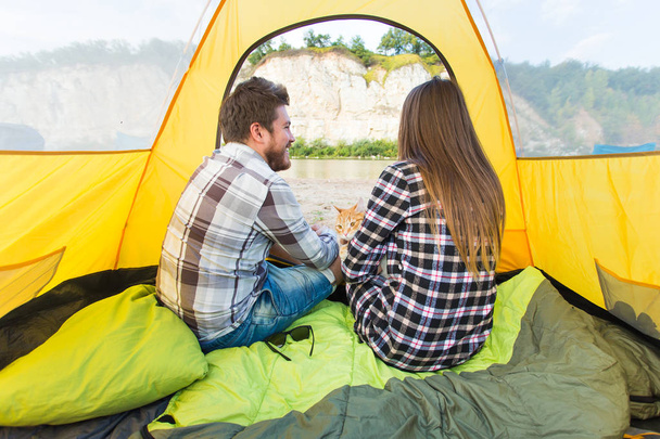 人、観光と自然の概念 - 黄色いテントの中で猫と座ってかわいいカップル - 写真・画像