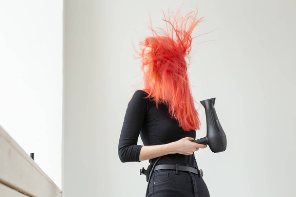 Stylistin, Mode, Friseur, People-Konzept - Frau trocknet ihre gefärbten Haare - Foto, Bild