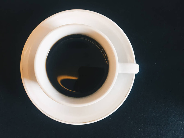 Café preto ou café expresso em uma xícara com vista superior isolada em fundo preto. acima de xícara de café
 - Foto, Imagem