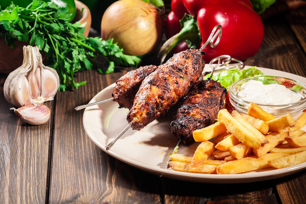 Grilled shish kebab served with fried chips and salad - Фото, изображение