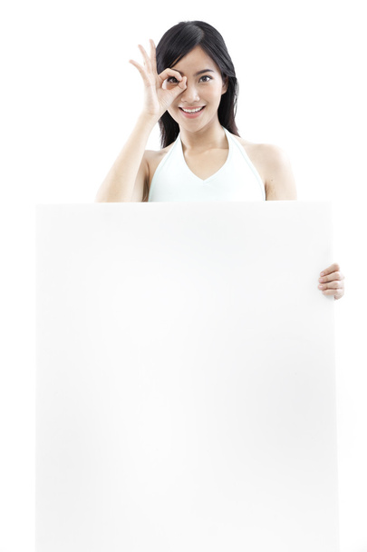 Casual woman standing behind a blank board on white background (green concept) - Photo, Image