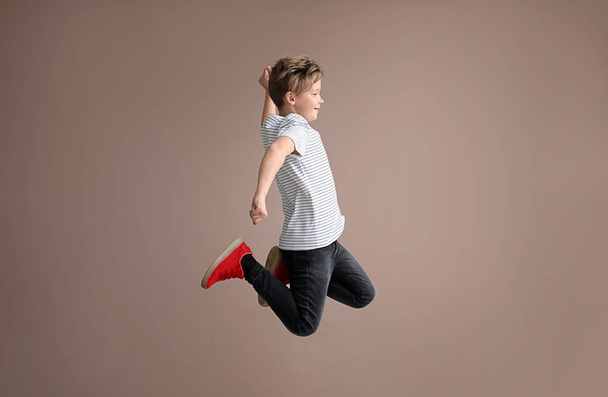 Springender kleiner Junge auf farbigem Hintergrund - Foto, Bild