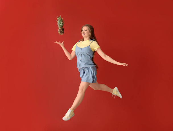Mujer saltando con piña sobre fondo de color
 - Foto, imagen