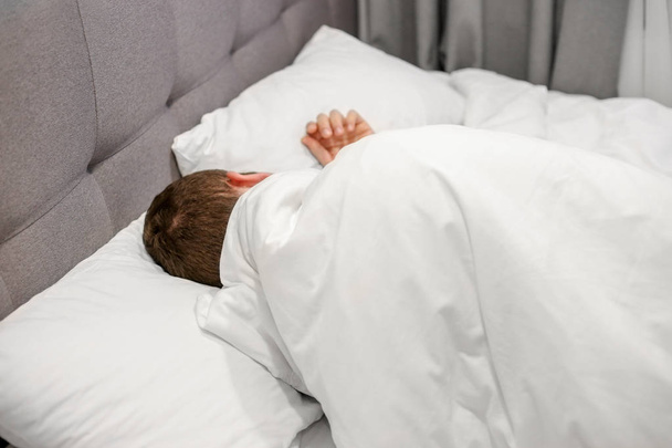 homem dormindo em uma cama branca
 - Foto, Imagem