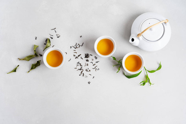 Asian set with green tea, cups and teapot on white background with green leaves  - Foto, Imagem