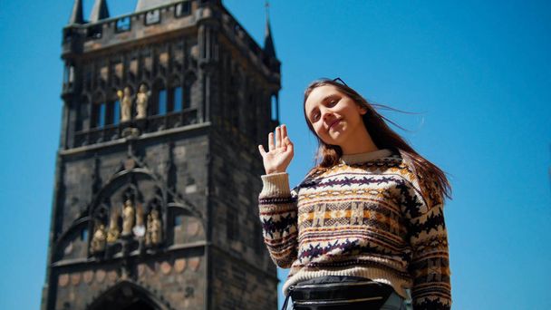 Giovane donna in posa per la foto e agitando la mano sullo sfondo della torre
 - Foto, immagini