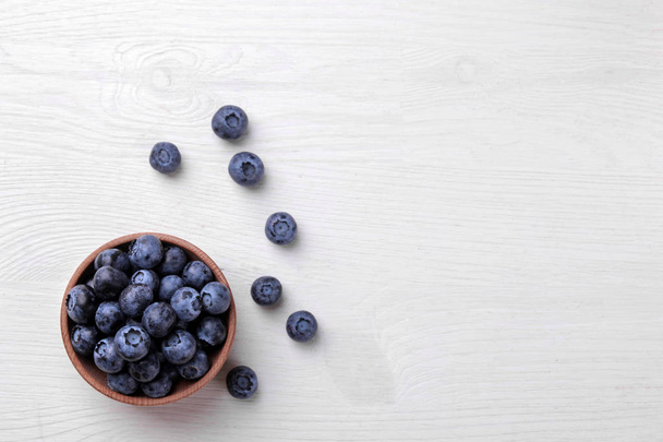 Вкусные черничные ягоды в миске на белом деревянном столе. место для смс. вид сверху
 - Фото, изображение