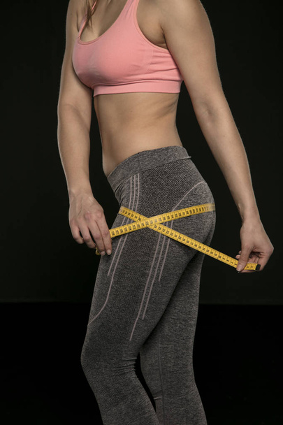 giovane donna con un corpo atletico utilizza un nastro di misurazione
 - Foto, immagini