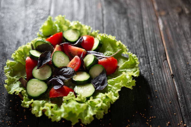 тарелка вкусного весеннего салата с овощами и зелеными листьями, оливковым маслом, специями
 - Фото, изображение