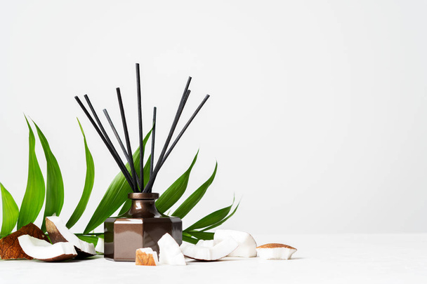 Aroma reed diffuser bottle home fragrance with rattan sticks and fresh coconut pieces on white background  - Fotografie, Obrázek