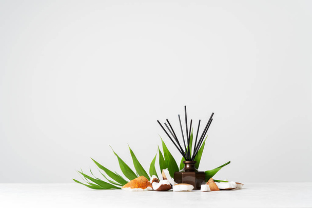 Aroma reed diffuser bottle home fragrance with rattan sticks and fresh coconut pieces on white background  - Fotó, kép