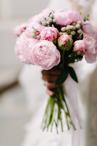 Bride in a wedding dress holding a wedding bouquet in her hands close-up - Фото, зображення