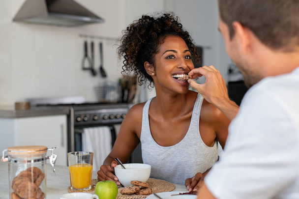 Man feeding cookie to woman for breakfast at home - Foto, immagini