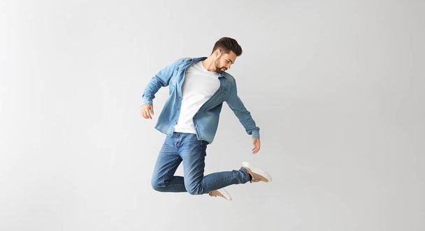 Jumping young man on light background - Foto, afbeelding