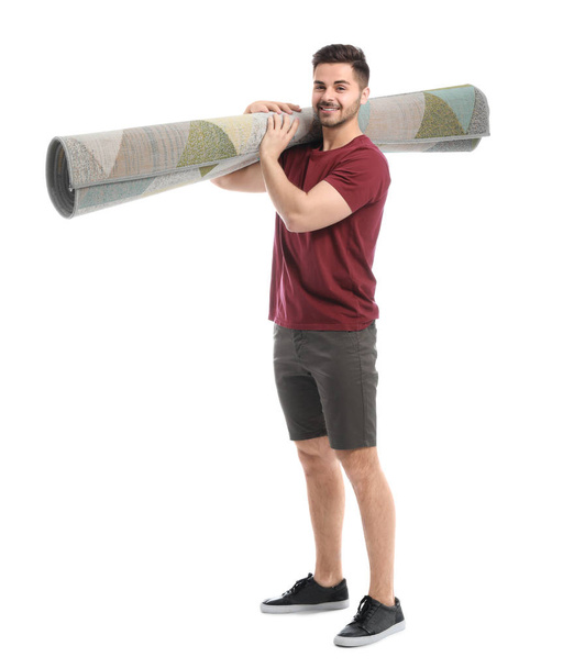 Young man holding rolled carpet against white background - Photo, Image