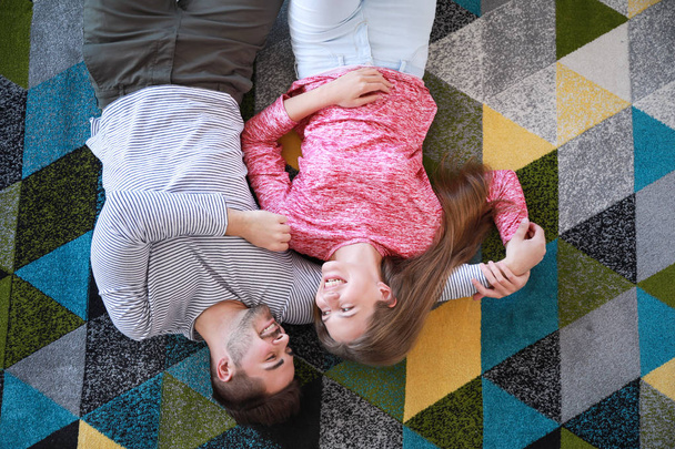 Молодая пара лежит на мягком ковре дома, вид сверху
 - Фото, изображение
