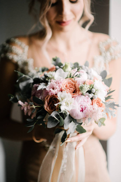Noiva em um vestido de noiva segurando um buquê de casamento em suas mãos close-up
 - Foto, Imagem