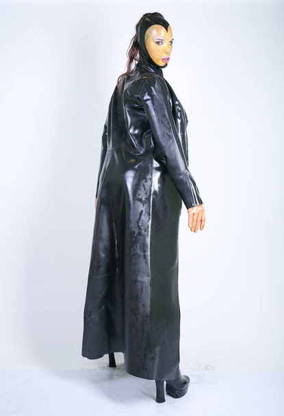 plus size woman in latex suit and leather boots in thick heavy rubber raincoat on white background in Studio. hot fashionable adult girl posing in fetish clothes alone isolated - Photo, Image