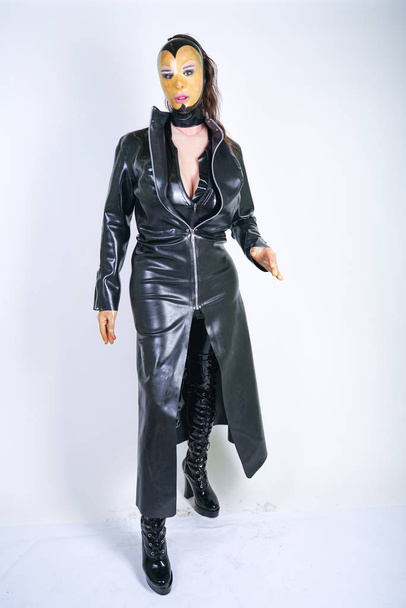 Plus size woman in latex suit and leather boots in thick heavy rubber raincoat on white background in Studio. hot fashionable adult girl posing in fetish clothes alone isolated hot - Фото, изображение