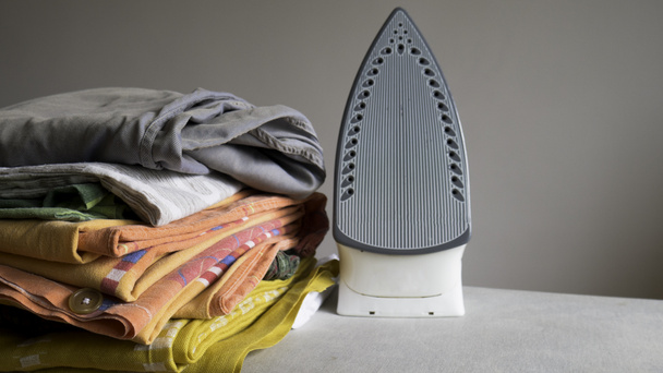 Electric iron and pile of clothes - Foto, afbeelding
