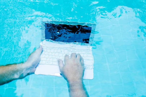水中で働くラップトップを持つ男性の手。作業中の障害物の概念。ぼかし抽象背景. - 写真・画像