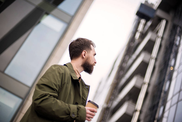 low angle view of handsome bearded man standing with disposable coffee cup on street - Valokuva, kuva