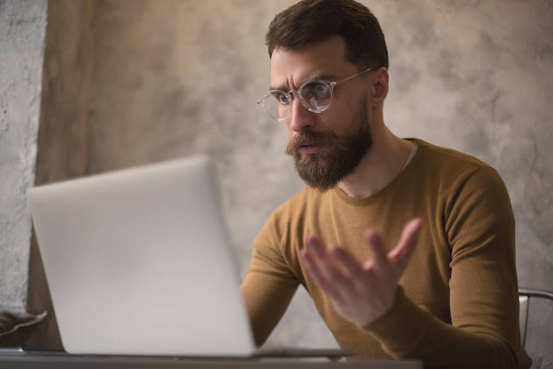 hombre barbudo enojado en gafas de trabajo en el ordenador portátil en la cafetería
 - Foto, Imagen