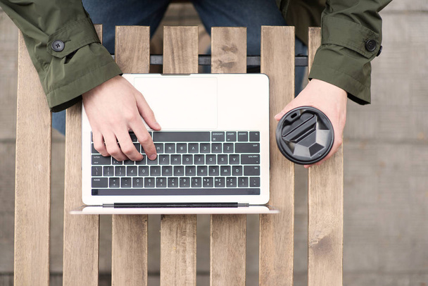 abgeschnittenes Bild eines Mannes, der am Laptop auf einem Holztisch arbeitet - Foto, Bild