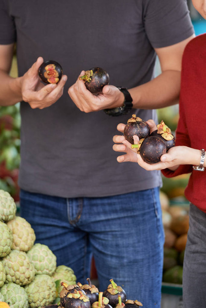 Handen van de paar winkelen voor ronde aubergines op de markt - Foto, afbeelding