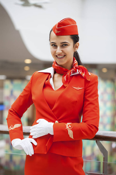 RUSSIA, MOSCOW: 28 JUNE 2019. Beautiful stewardess dressed in official red uniform of Aeroflot Airlines on airport - Foto, afbeelding