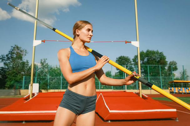 Female high jumper training at the stadium in sunny day - Foto, imagen