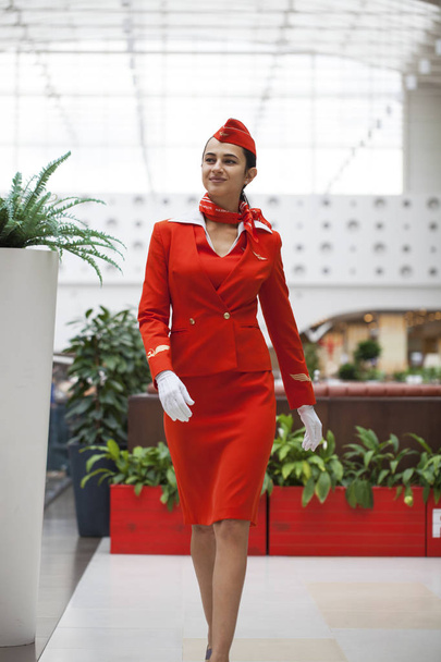 RUSSIA, MOSCOW: 28 JUNE 2019. Beautiful stewardess dressed in official red uniform of Aeroflot Airlines on airport - Foto, Imagen