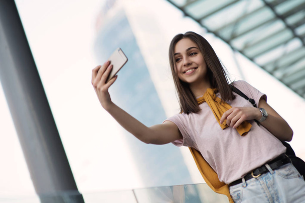 Ładna kobieta podróżuje po centrum miasta w stolicy nowego kraju mówi selfie siebie i uśmiechnięty. Lubi swoje wakacje i cieszyć się technologią na telefon komórkowy i nowoczesne połączenie z Internetem - Zdjęcie, obraz