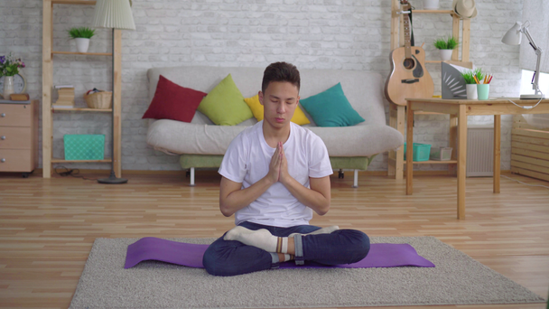 Fiatal koreai ember csinál jóga ül a szőnyegen - Felvétel, videó