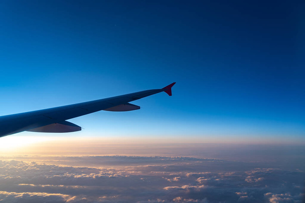Nahoře ve vzduchu, pohled na siluetu letadla s tmavomodrým obzorem a pozadí mraků v době vzestupu slunce, viděno z okna letadla - Fotografie, Obrázek