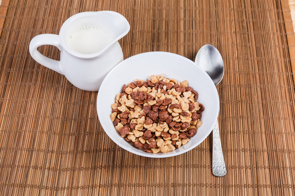 Breakfast cereal, milk and spoon on the bamboo table mat - Photo, Image