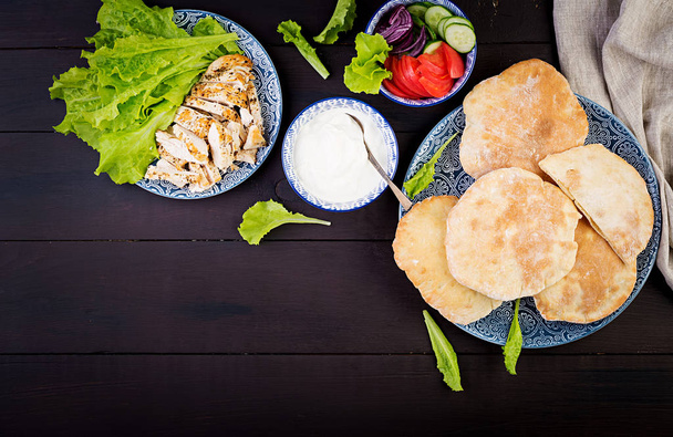 Pita farcie au poulet, tomate et laitue sur fond bois. Cuisine du Moyen-Orient. Vue du dessus
 - Photo, image