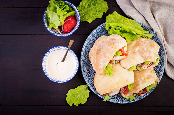 Pita farcita con pollo, pomodoro e lattuga su fondo di legno. Cucina mediorientale. Vista dall'alto
 - Foto, immagini