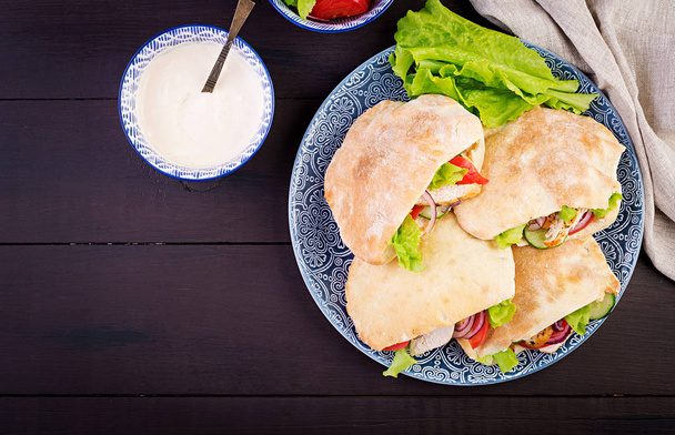 Pita stuffed with chicken, tomato and lettuce on wooden background. Middle Eastern cuisine. Top view - Photo, Image