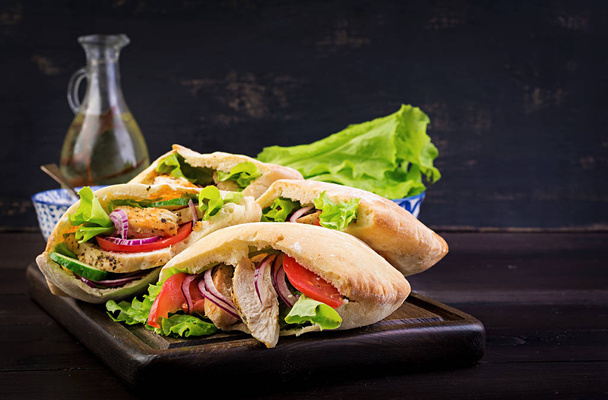 Pita stuffed with chicken, tomato and lettuce on wooden background. Middle Eastern cuisine. - Φωτογραφία, εικόνα