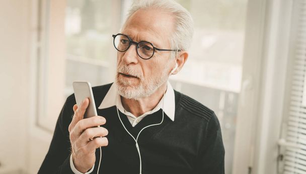 Businessman using earphones during conversation on mobile phone - Valokuva, kuva