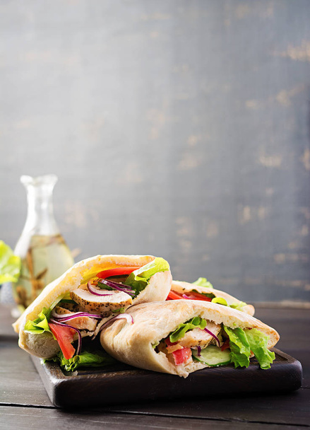 Пита фаршированная курицей, помидорами и салатом на деревянном фоне. Ближневосточная кухня
. - Фото, изображение
