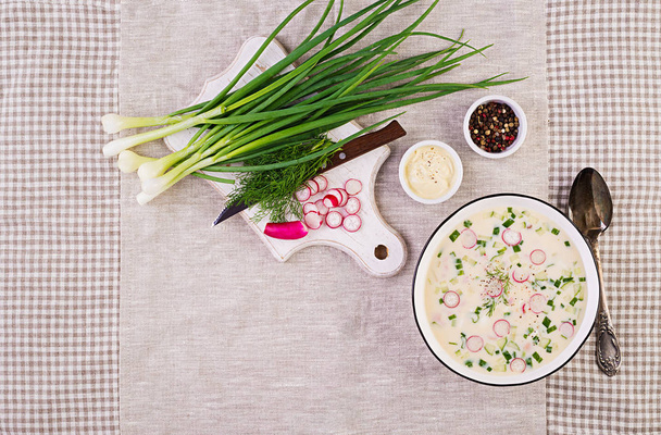 Soupe froide aux concombres frais, radis, pommes de terre et saucisses avec yaourt dans un bol. Nourriture russe traditionnelle okroshka. Soupe froide d'été. Vue de dessus. Pose plate
 - Photo, image
