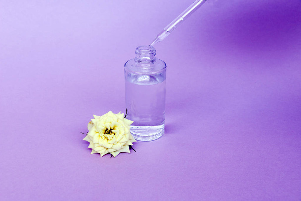 Glass bottle with pipette with oil or serum, with white rose flower on delicate background. Concept: organic bio cosmetics, vegetable oils, serum collagen, skin care - Zdjęcie, obraz