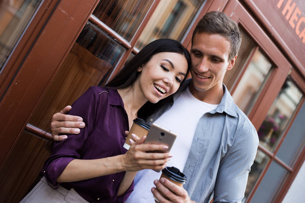glückliches junges Paar mit Einweg-Kaffeetassen und Smartphone - Foto, Bild