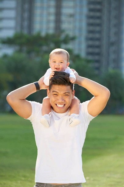 Feliz joven asiático hombre con bebé niño sentado en su cuello
 - Foto, imagen