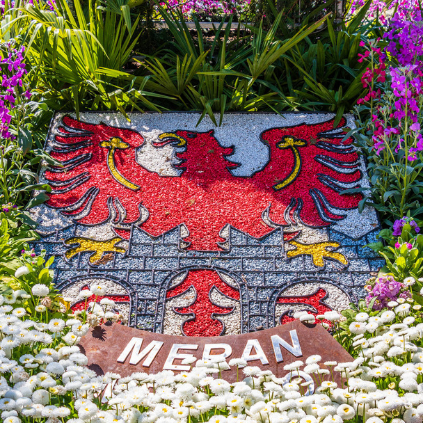 Naturalny grzebień, godło, flaga miasta Meran w kwietniku i roślinności. Merano. Prowincja Bolzano, Południowy Tyrol, Włochy. Europa. - Zdjęcie, obraz